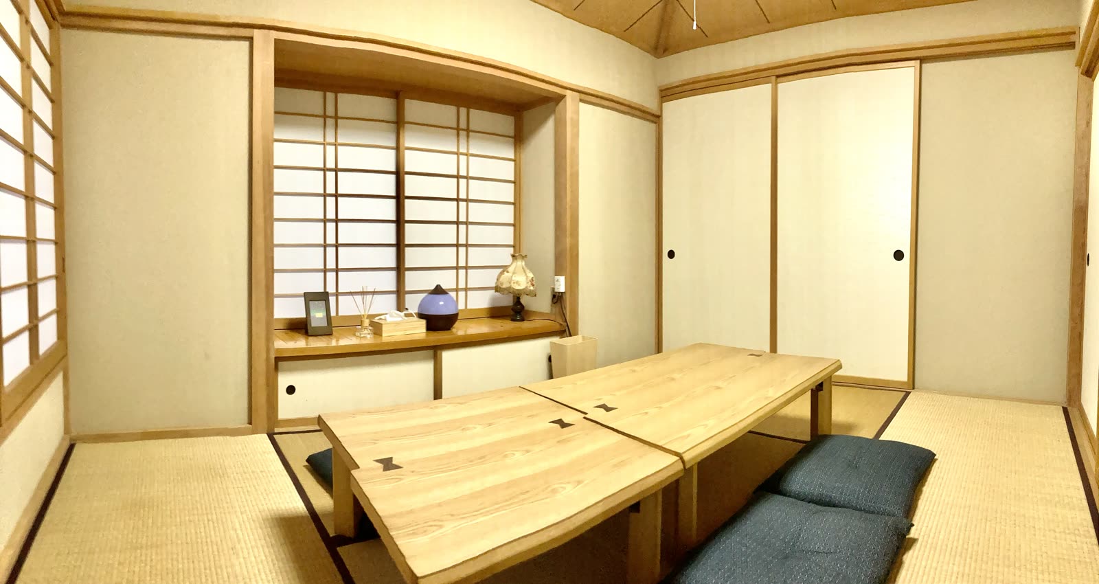障子の出窓と襖のある6畳の和室。木の座卓と座布団を置いている